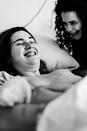 Two women sharing a joyful laugh together in a black and white portrait photo.