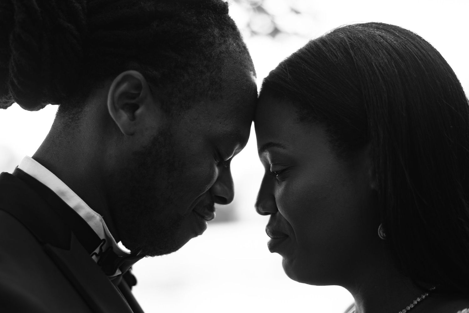 Black and white portrait of two people facing each other with foreheads nearly touching in an intimate moment.