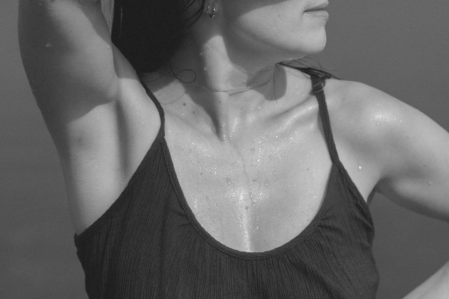 Partner gently touching pregnant woman's belly outdoors in warm golden sunlight.