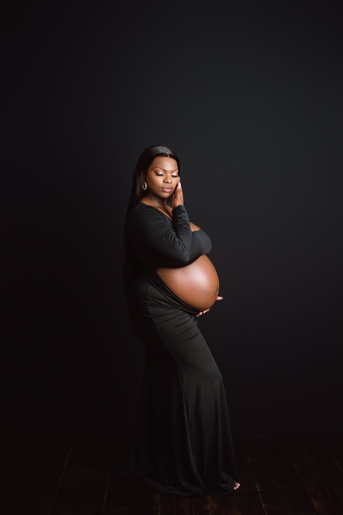 Pregnant woman with eyes closed enjoying a peaceful moment during maternity photoshoot