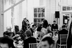 Black and white wedding reception with live band performing for elegantly dressed guests seated at decorated tables.
