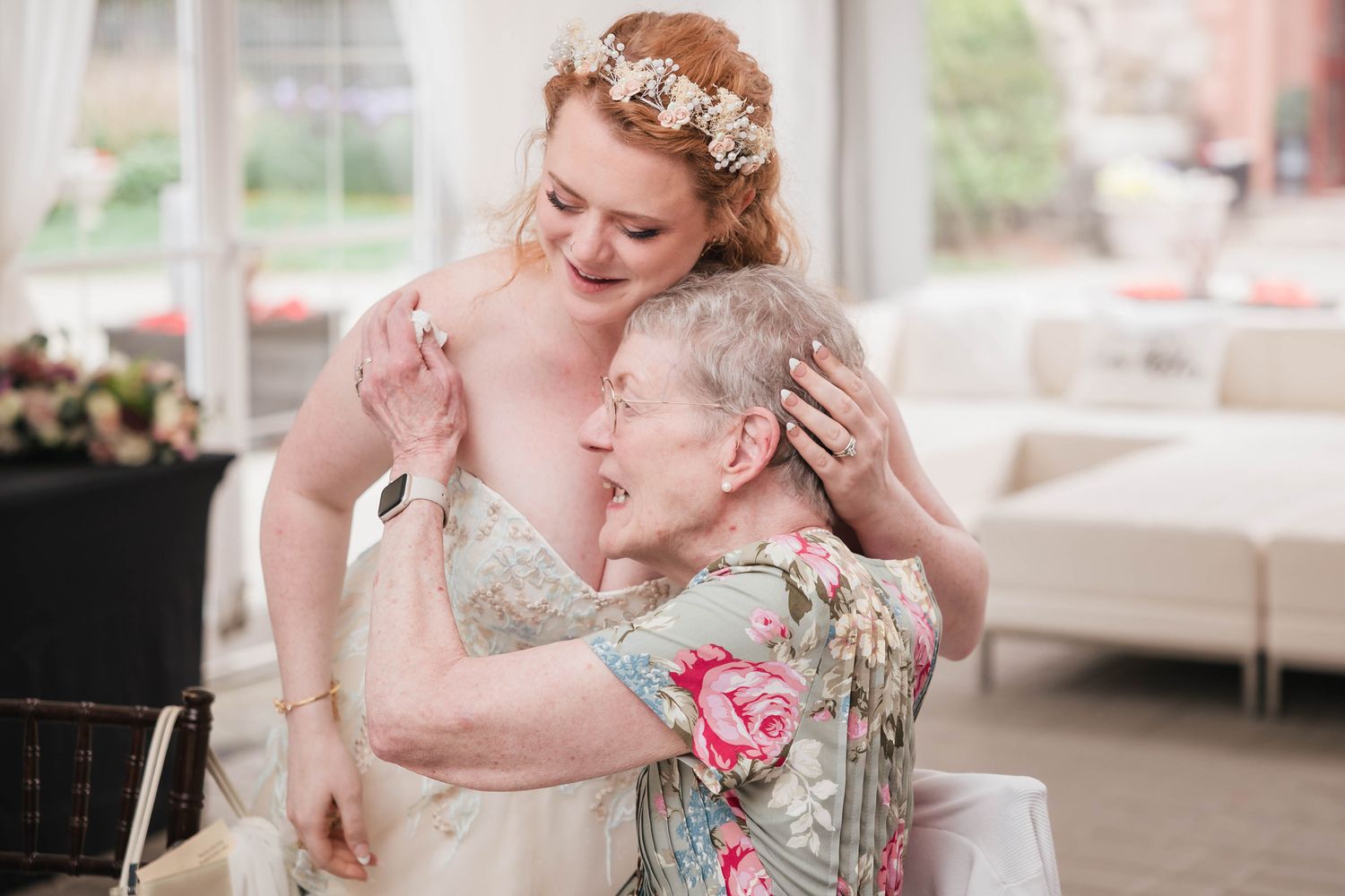 Bride embracing her grandmother during the reception, both smiling with tears in their eyes.