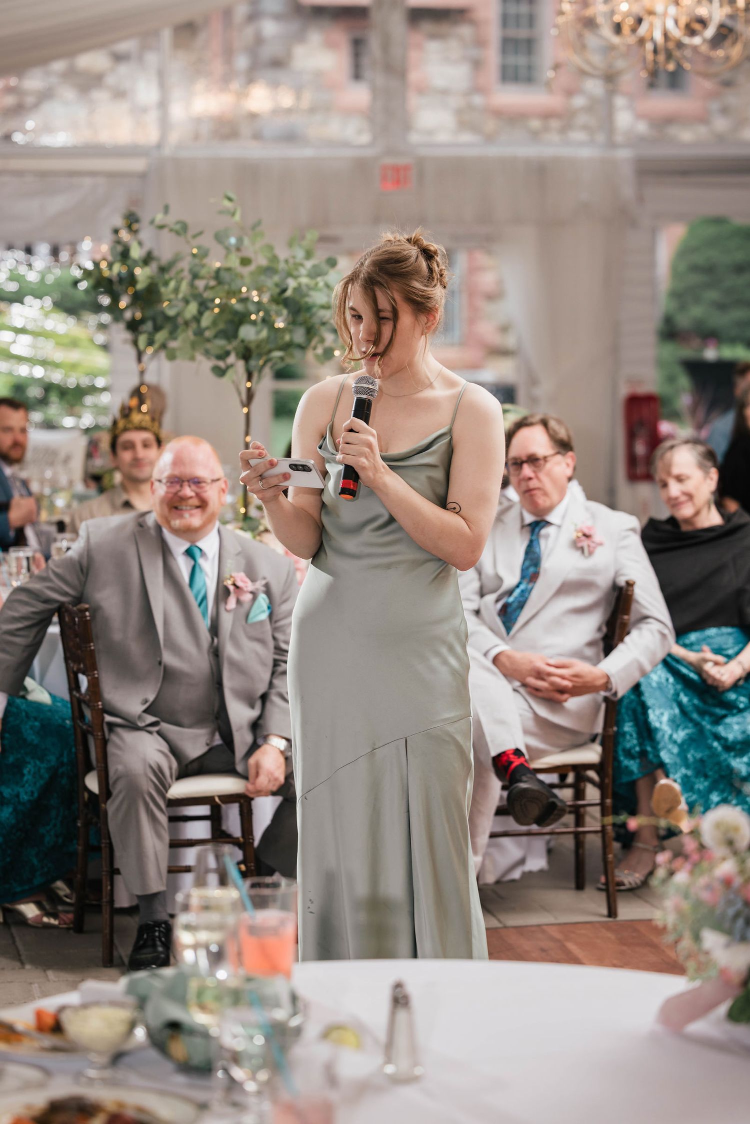 Bridesmaid reading her speech from her phone, hair falling across her face.