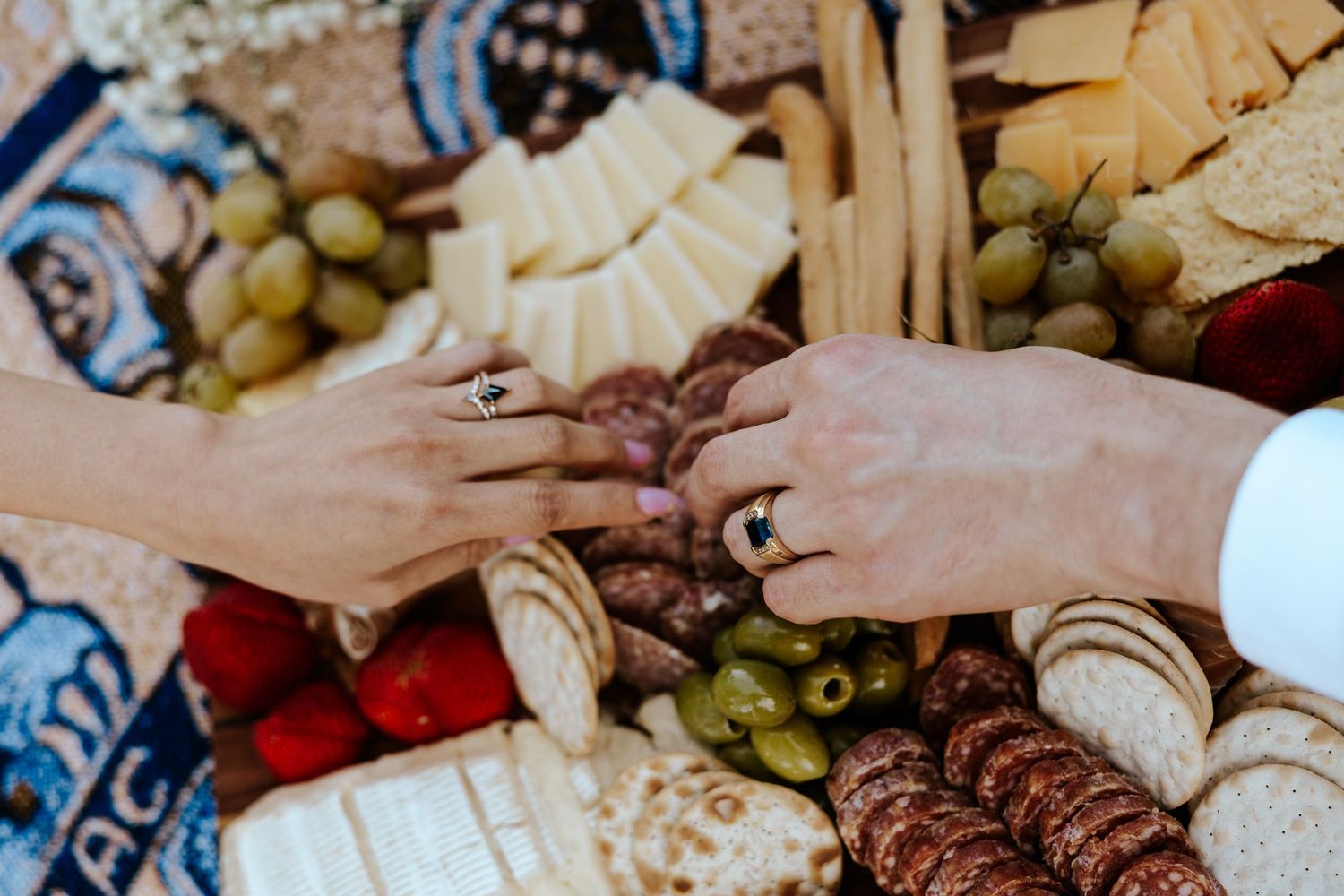 up close photo of bride and groom's hands reaching over charcuterie board during elopement picnic