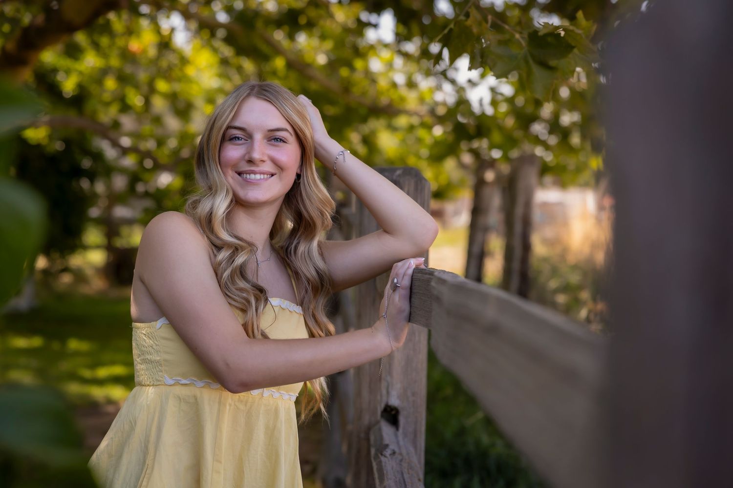 girl wearing yellow tank top leaning on fence