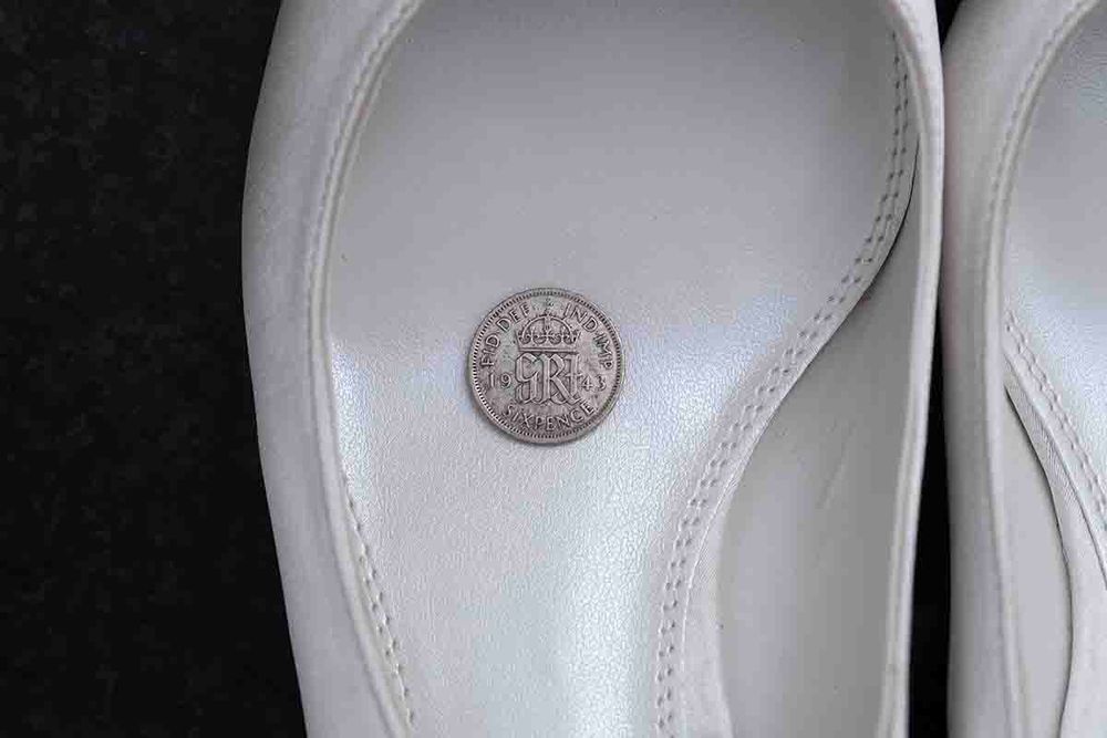 White bridal shoes with a lucky sixpence coin placed inside the insole, a traditional wedding good luck charm.
