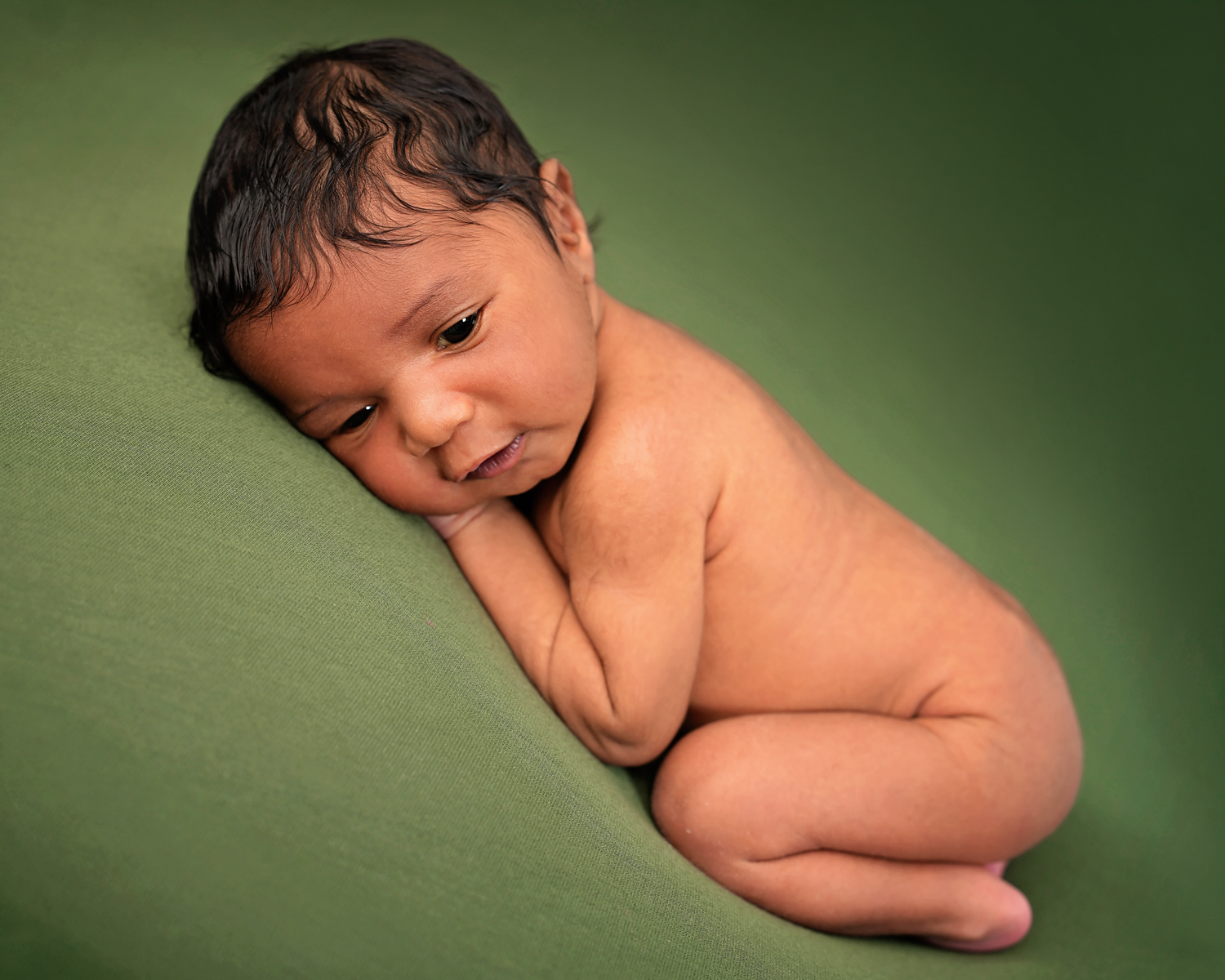 Ten-day-old newborn baby posed naturally on a soft green backdrop during a Herndon newborn photography session.