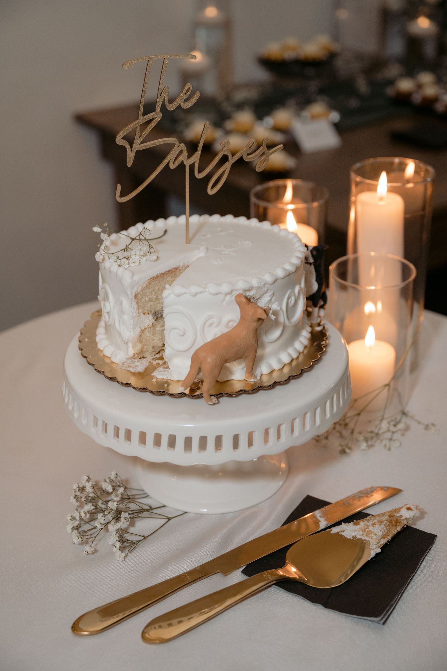 Candle lit wedding cake with a dog figurine eating cake out of the side during an Abella Weddings & Events wedding in Chisago City, MN.