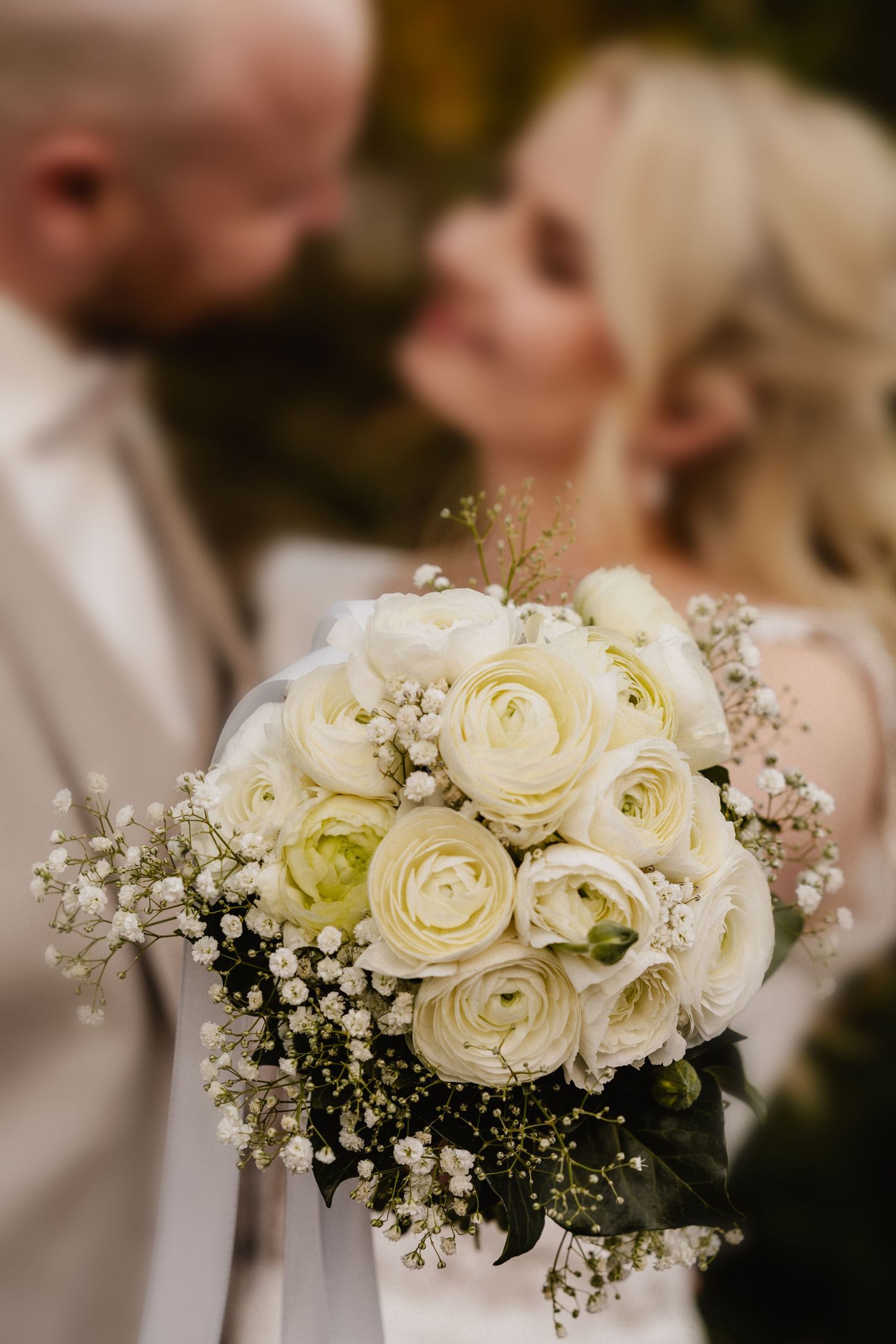 Black and white photo of a bride and groom sharing their first dance in an elegant venue with arched doorway.
