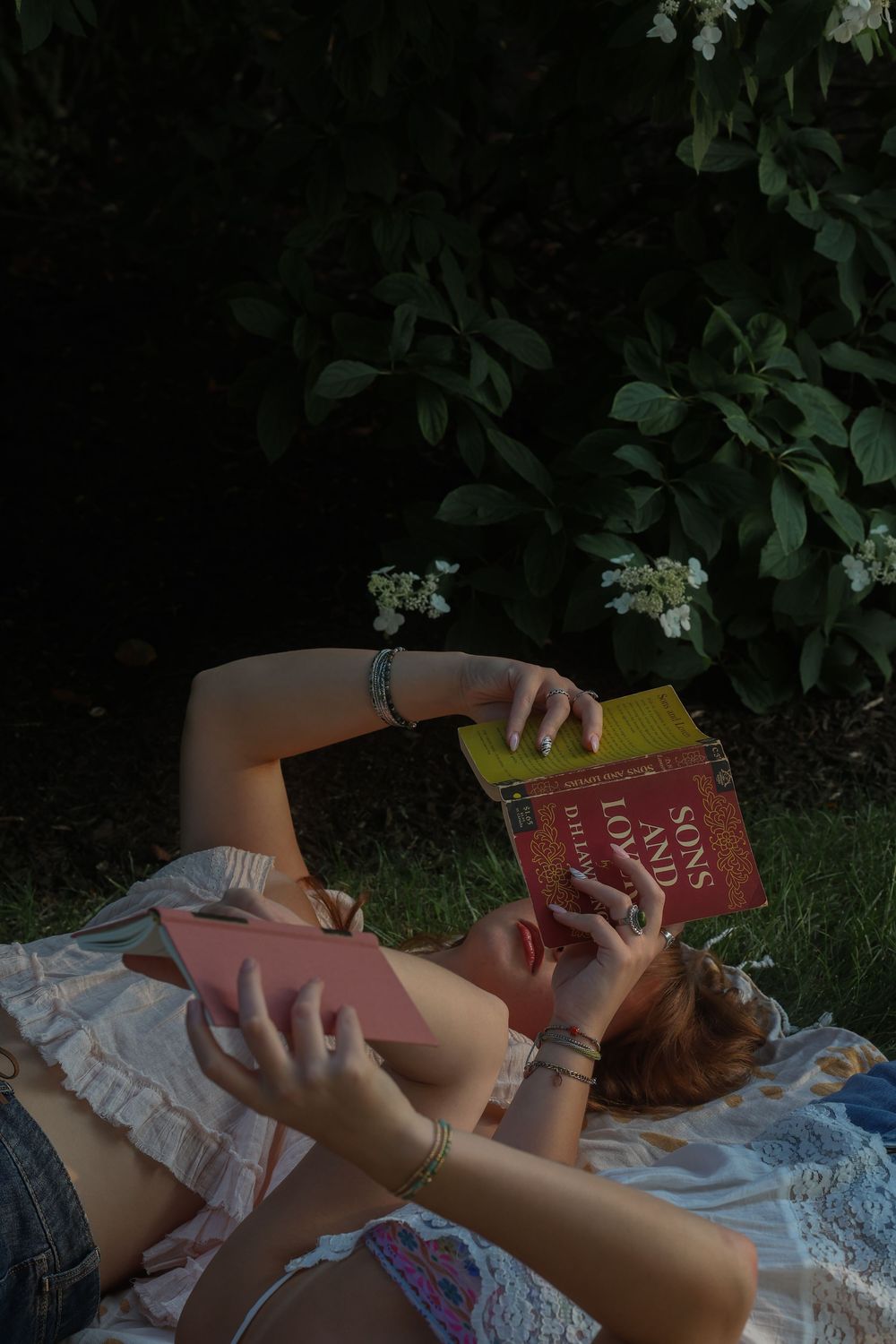 Two women lying on picnic blanket and reading independently