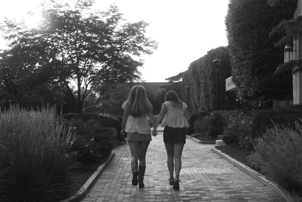Two women holding hands and walking away
