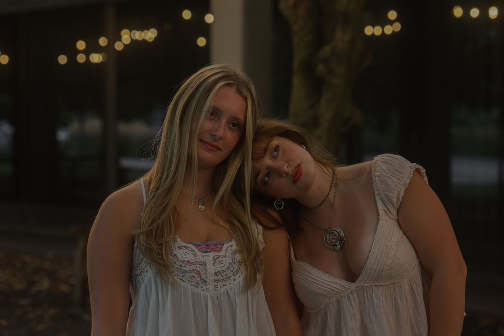 Two women posing and lookingoff  into the distance