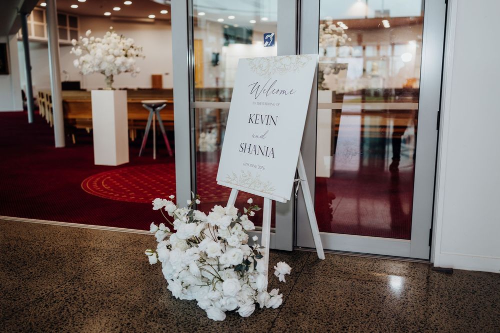 Elegant wedding welcome sign for Kevin and Shania with white floral decorations.