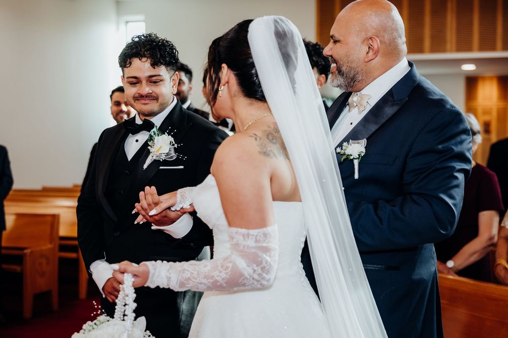 A groom exchanges vows with his bride in a lace wedding dress at a church ceremony.