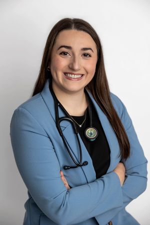 Smiling female healthcare professional in blue blazer with stethoscope, arms crossed, posing for professional headshot.