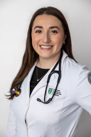 A smiling female medical student in a white lab coat with stethoscope from Ohio College of Osteopathic Medicine poses professionally.