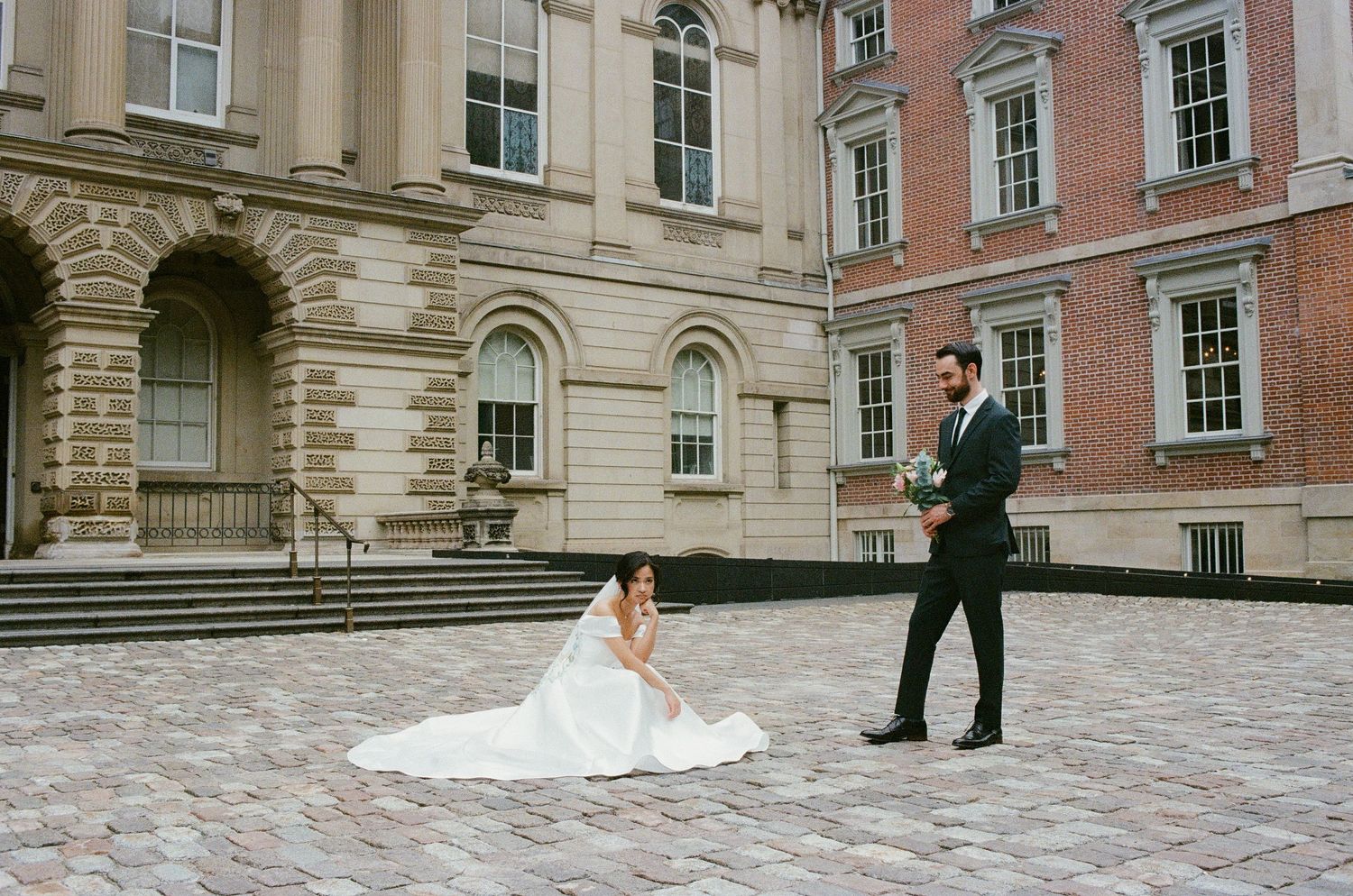 Couple poses in gothic archway with dramatic windows and natural light.