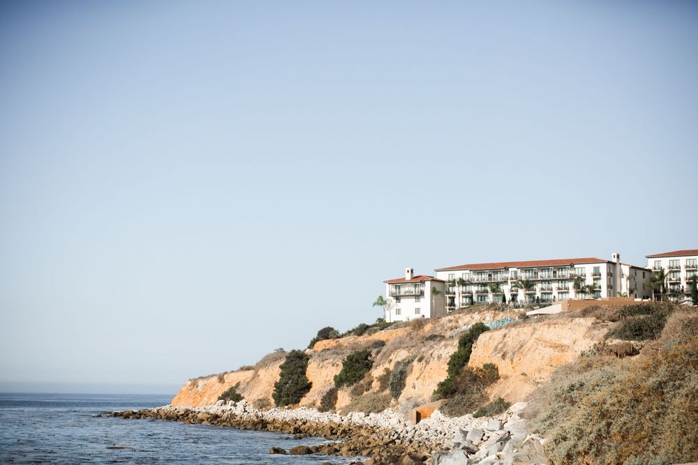 Luxury hotel perched on coastal cliffs overlooking the ocean under a clear blue sky.