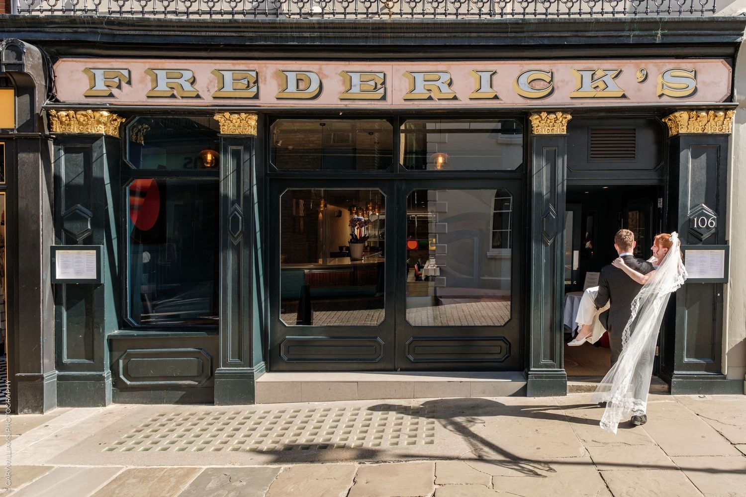 Couple dancing outside Frederick's restaurant with elegant green and gold Victorian shopfront facade.