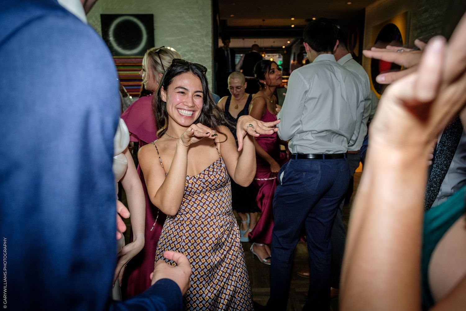 Woman in polka dot dress smiling and dancing at a lively wedding reception party.