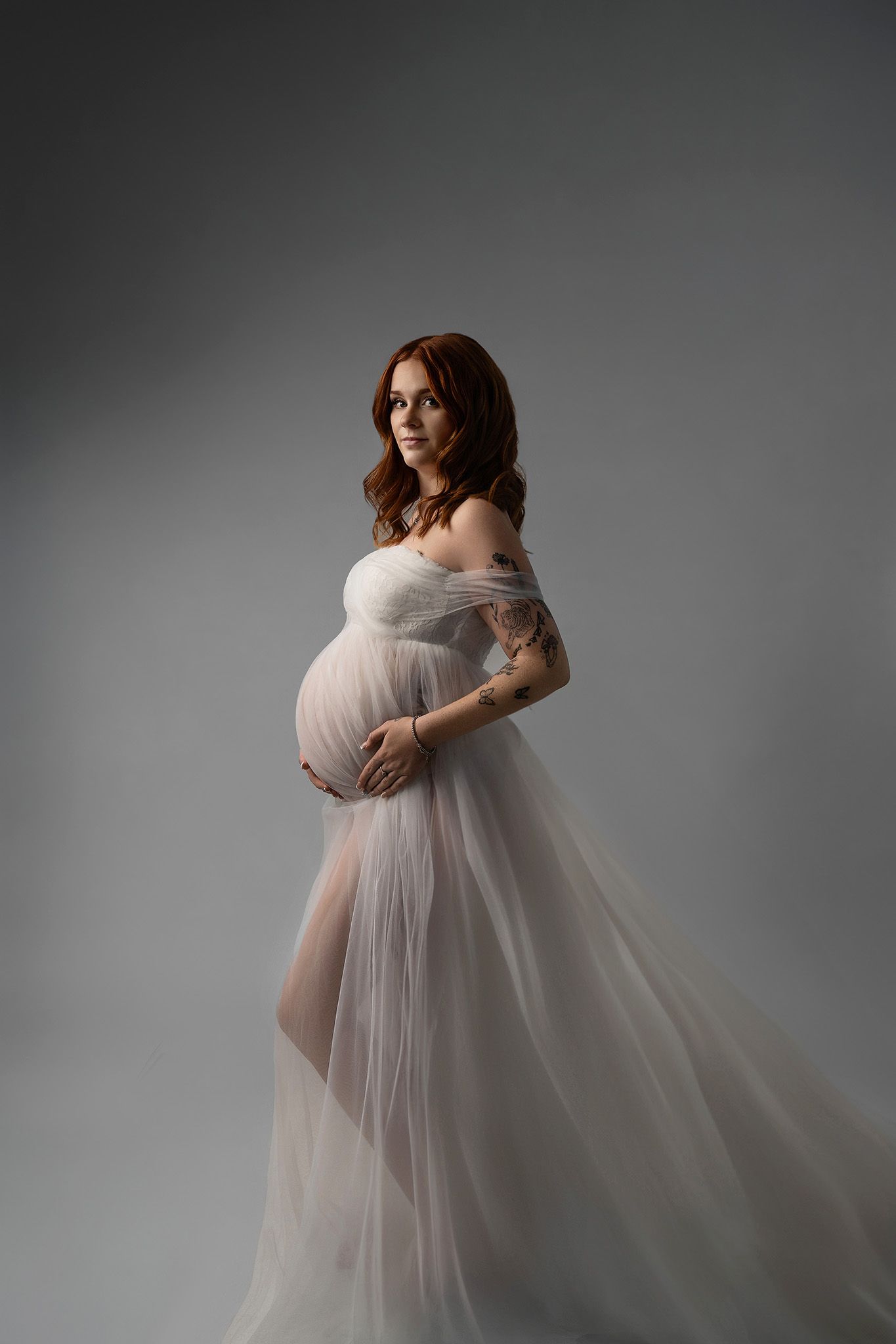 Pregnant woman with flowers during maternity session in studio