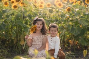 Children pose playfully among tall sunflowers during a summer photo session in the Hudson Valley,NY.