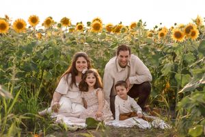 A family portrait session nestled among blooming sunflowers during golden hour.