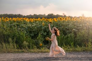 A flowing dress twirls gracefully among towering sunflowers at sunset in the Hudson Valley,NY.