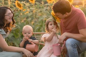 Happy family shares intimate moment together among blooming sunflowers at golden hour.