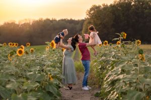 A joyful sunset moment in a sunflower field as figures play and dance together at golden hour.