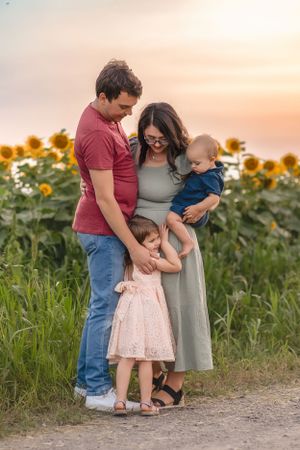 A tender family moment among sunflowers during a golden sunset.