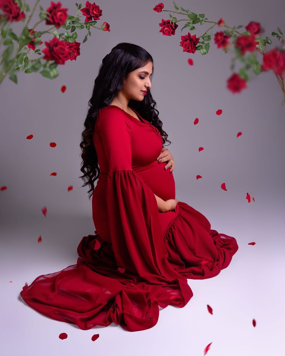 Pregnant woman in a red dress holding baby bump, studio session in Wolverhampton