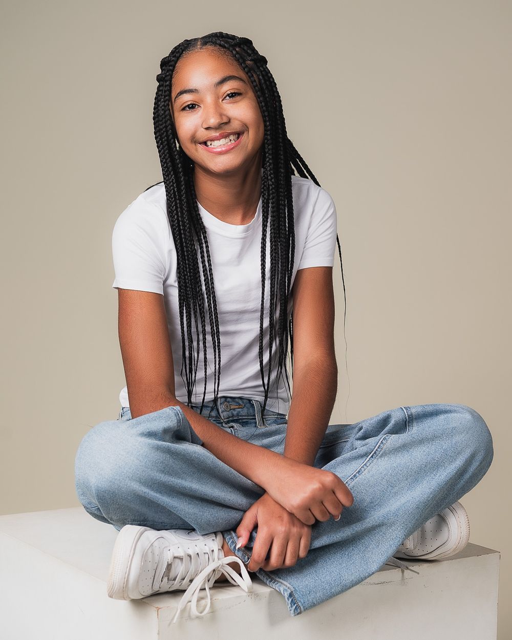 Casual portrait of a person in white t-shirt and jeans sitting cross-legged.