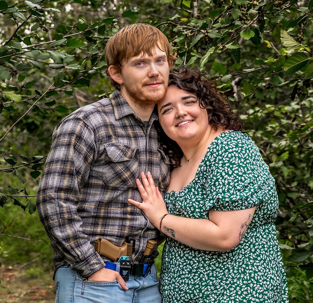 A couple in plaid and green prints share joyful moments outdoors among lush greenery in a casual photo series.