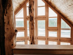 Rustic wooden window frame with panoramic mountain lake view.