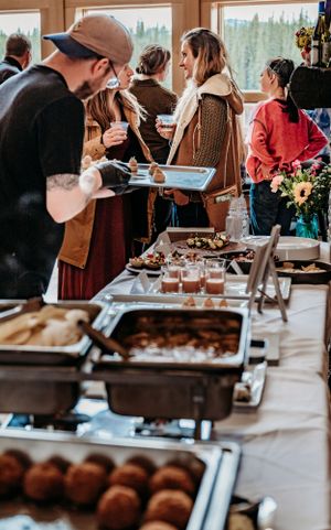 Buffet line with chafing dishes and servers at a casual event.
