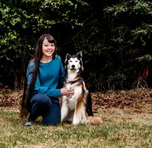 A husky mix dog poses with their companion in a grassy outdoor setting.