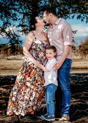 A family shares a joyful embrace outdoors against a natural landscape.