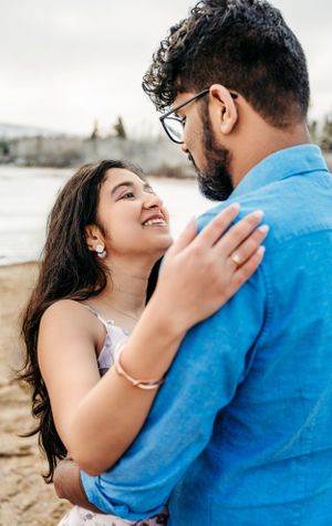 A romantic couple embracing outdoors with mountains in the background.
