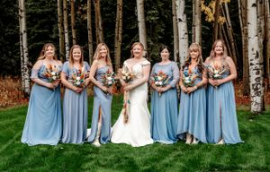 Wedding party in light blue dresses poses together in front of birch trees and autumn foliage.