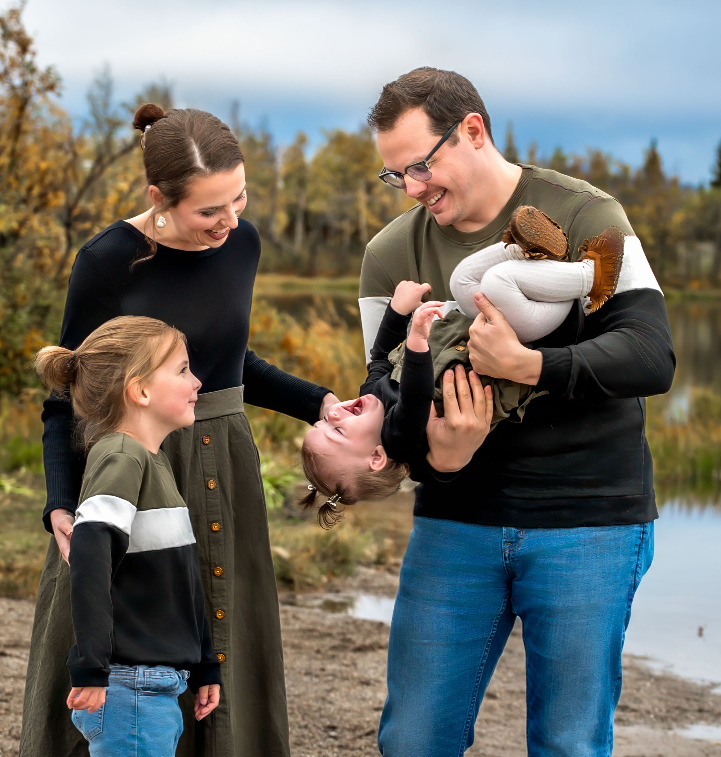 A family shares a joyful moment together on an autumn day by the water's edge.
