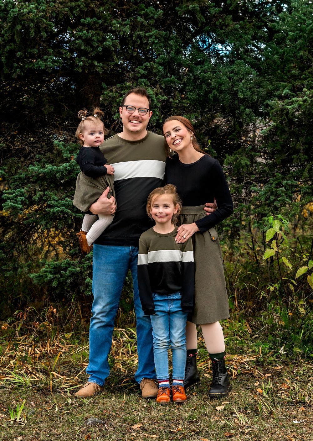 A group poses together outdoors against a natural backdrop of green foliage and autumn colors.