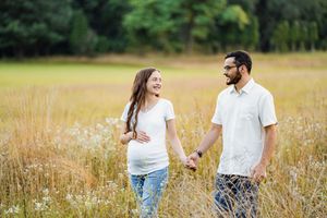 Sweet couple enjoying a romantic stroll together through a sunlit meadow of tall grass and wildflowers.