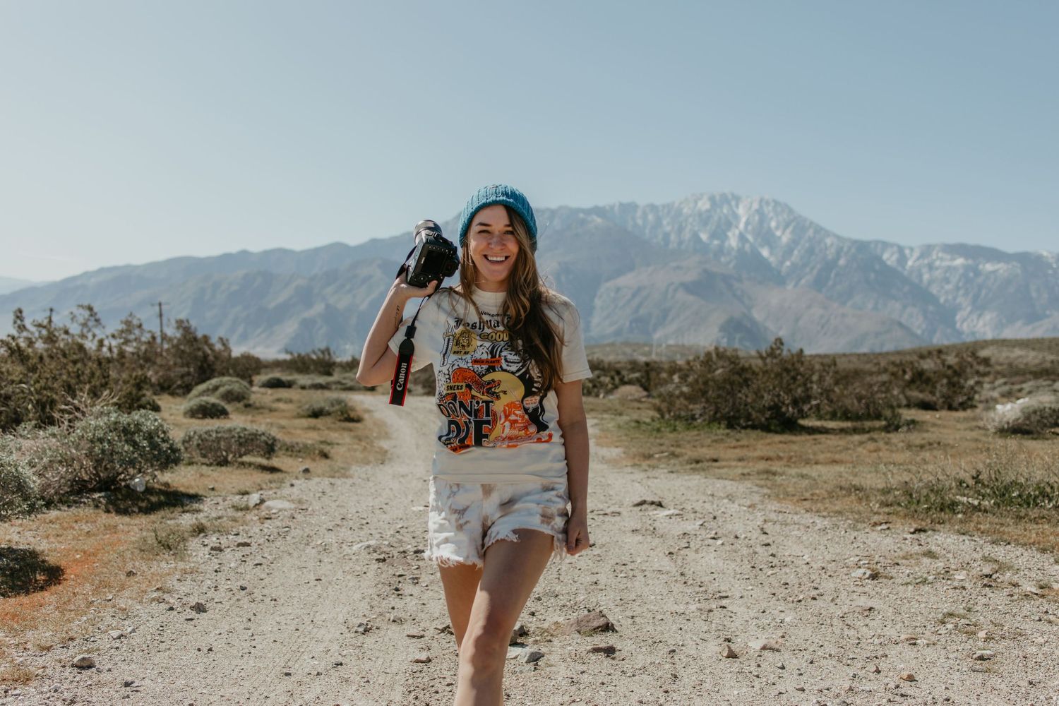 Person hiking through desert landscape with mountains visible in background.