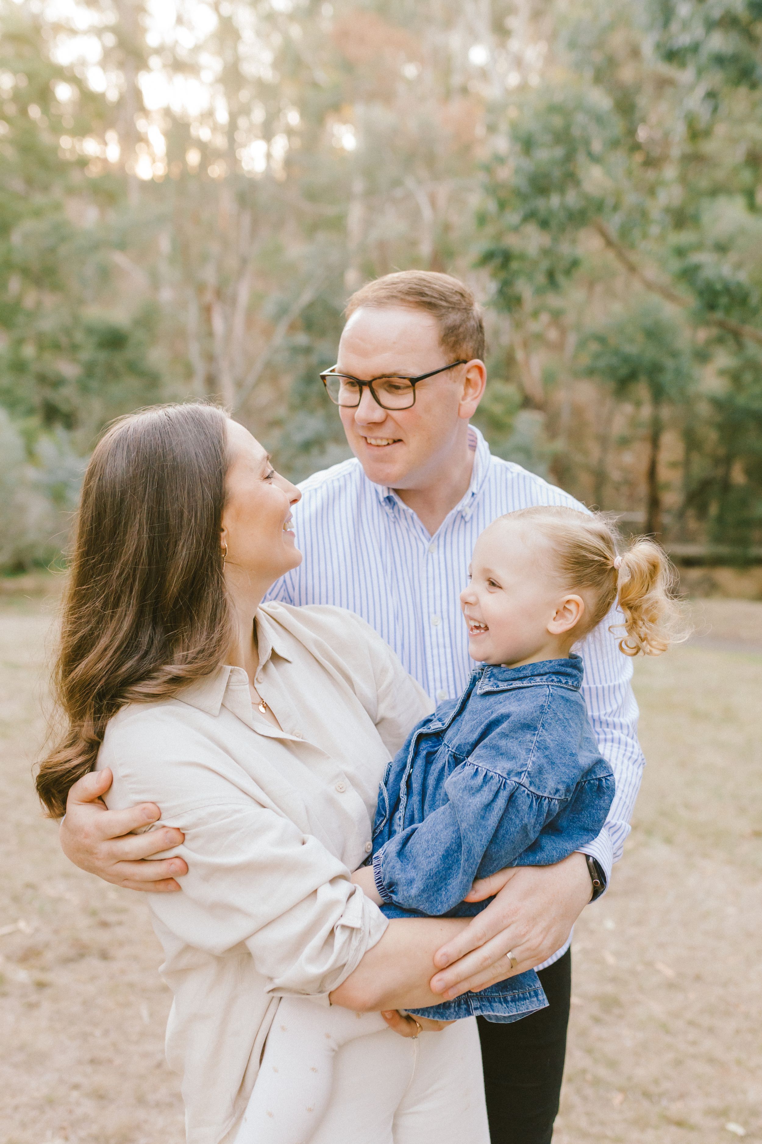 A family shares joyful candid moments together outdoors in a natural setting during a photo session.