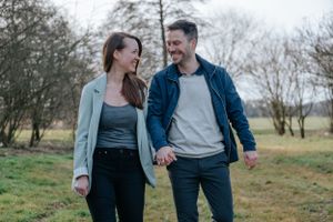 Ein lachendes Paar, Hand in Hand auf die Kamera zugehend.