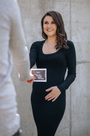 Familienfotografie: Schwangere Frau hält ein Ultraschallbild in den Händen, natürliche Aufnahme im Raum Dachau.