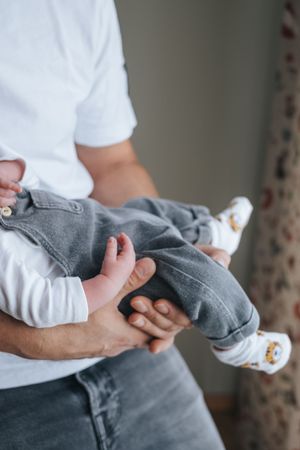 Babyfotografie: Neugeborenes liegt im Arm eines Elternteils, ruhige Aufnahme im häuslichen Umfeld.