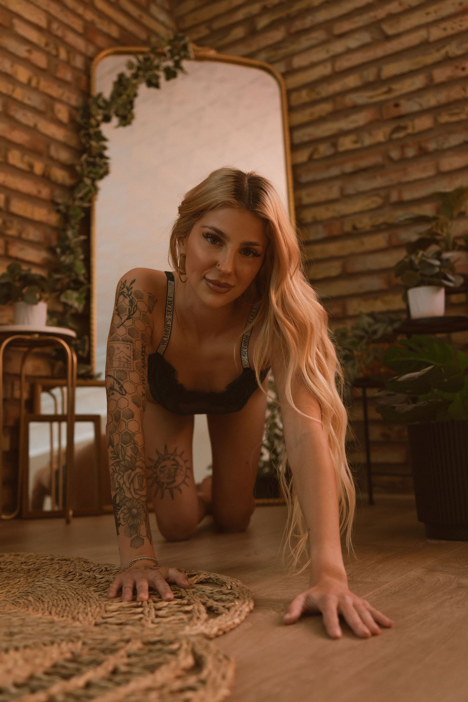 Artistic boudoir photo in warm tones with brick wall backdrop and decorative ivy details.