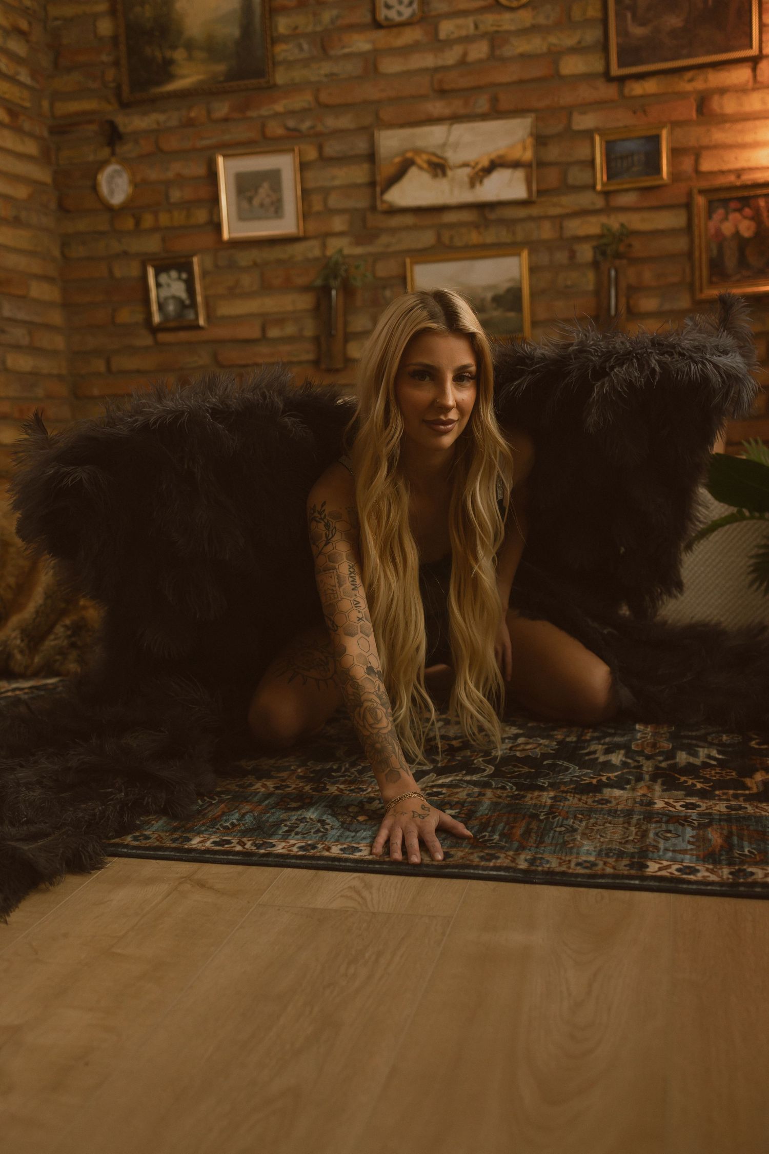 Person crawling on wooden floor next to patterned rug in warmly lit room with exposed brick walls.